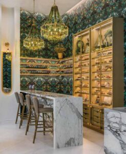 Marble countertops facing peacock wallpaper and retail shelves for high-end eyewear designed by JL Studios at Eye Wares in New Orleans, LA, as featured in Inside New Orleans Magazine